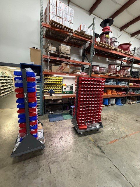 Two vertical storage racks filled with colorful plastic bins in a warehouse.
